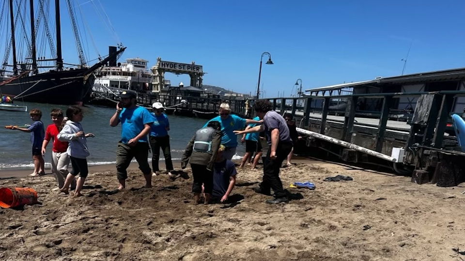 Participants in the Maritime Explorer Club day camp digging for hidden treasure on the beach.